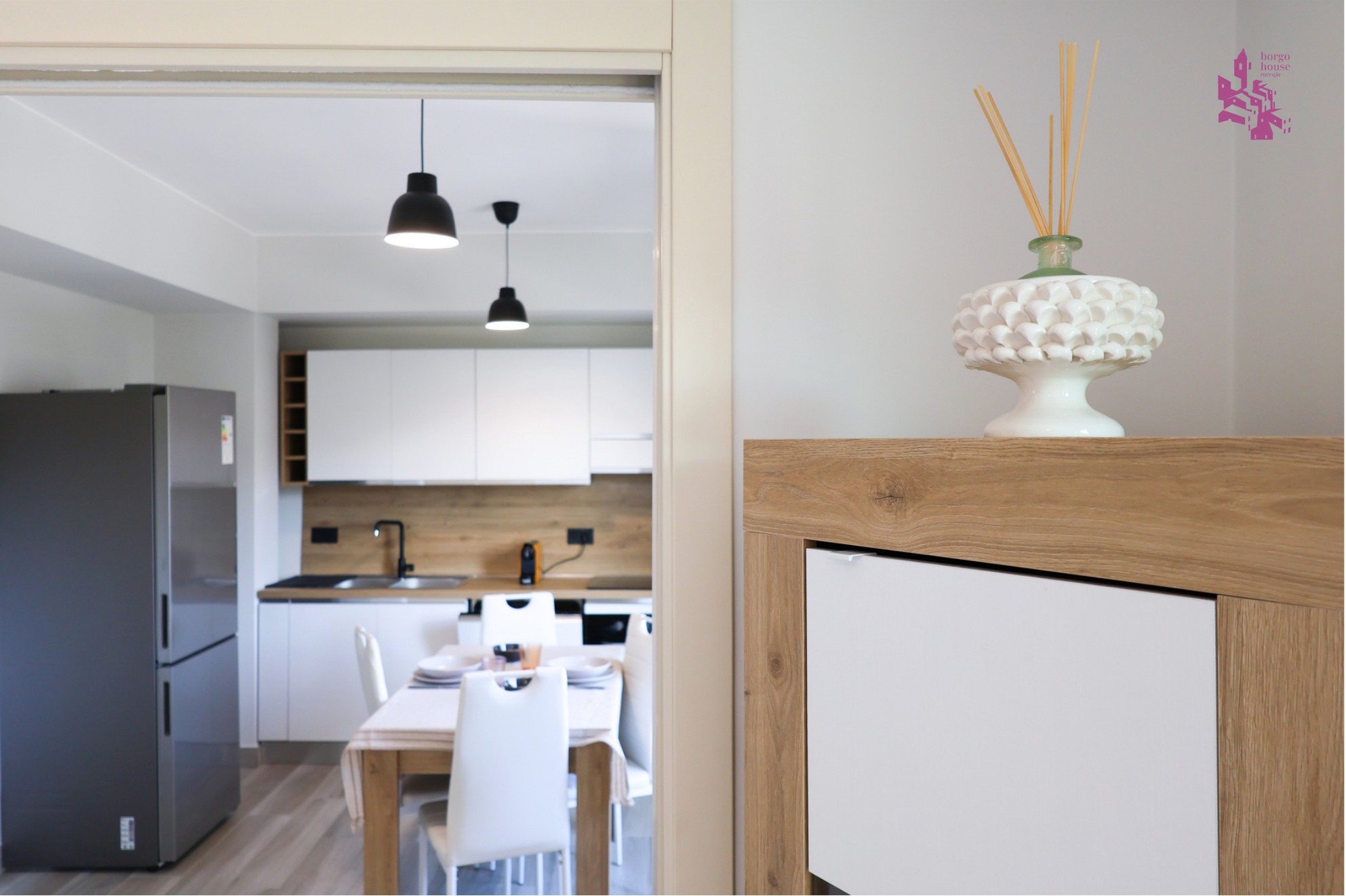 Cucina lineare di Borgo House con piani in legno chiaro e zona pranzo