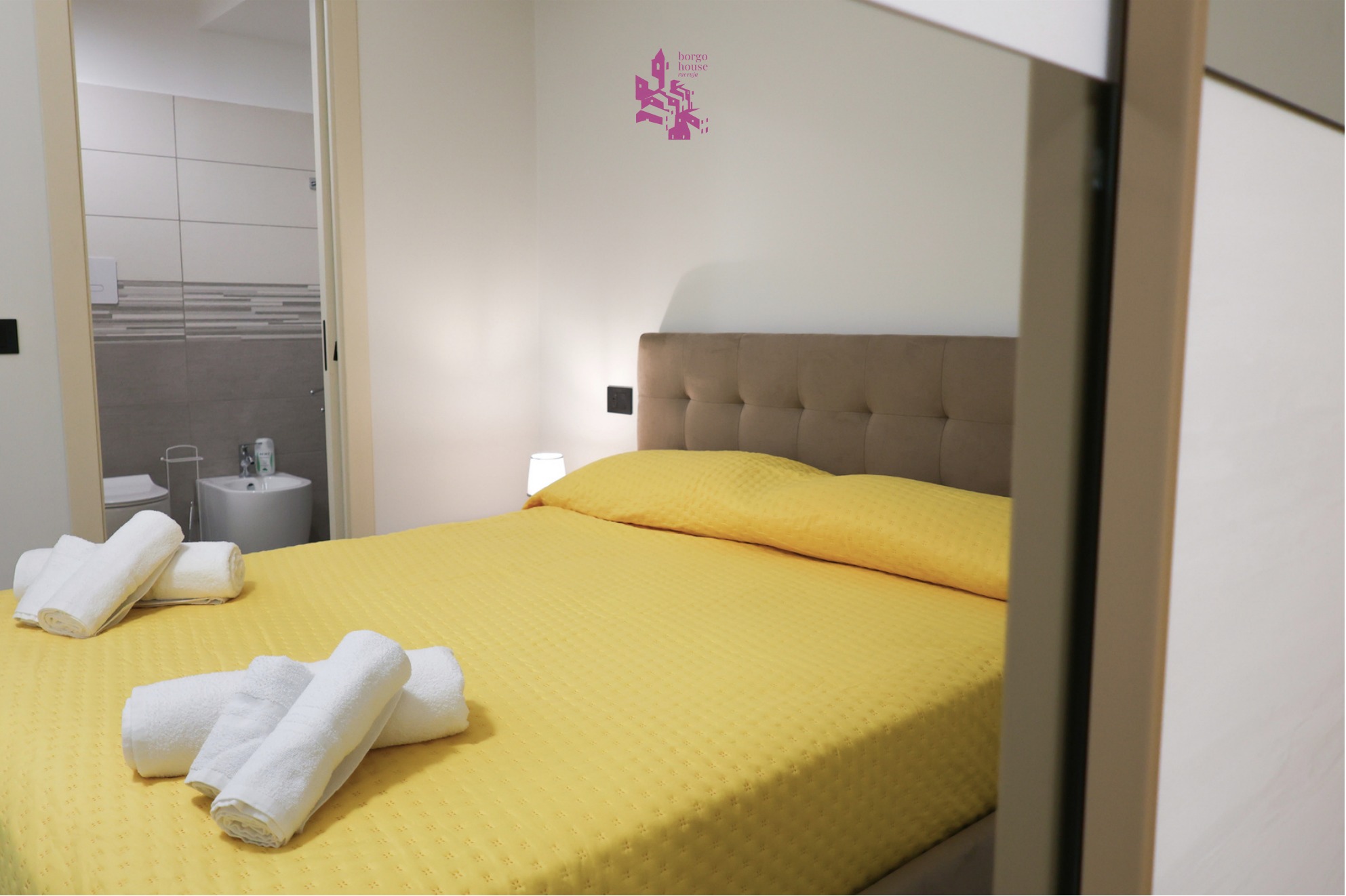 Camera con copriletto giallo e affaccio sul bagno