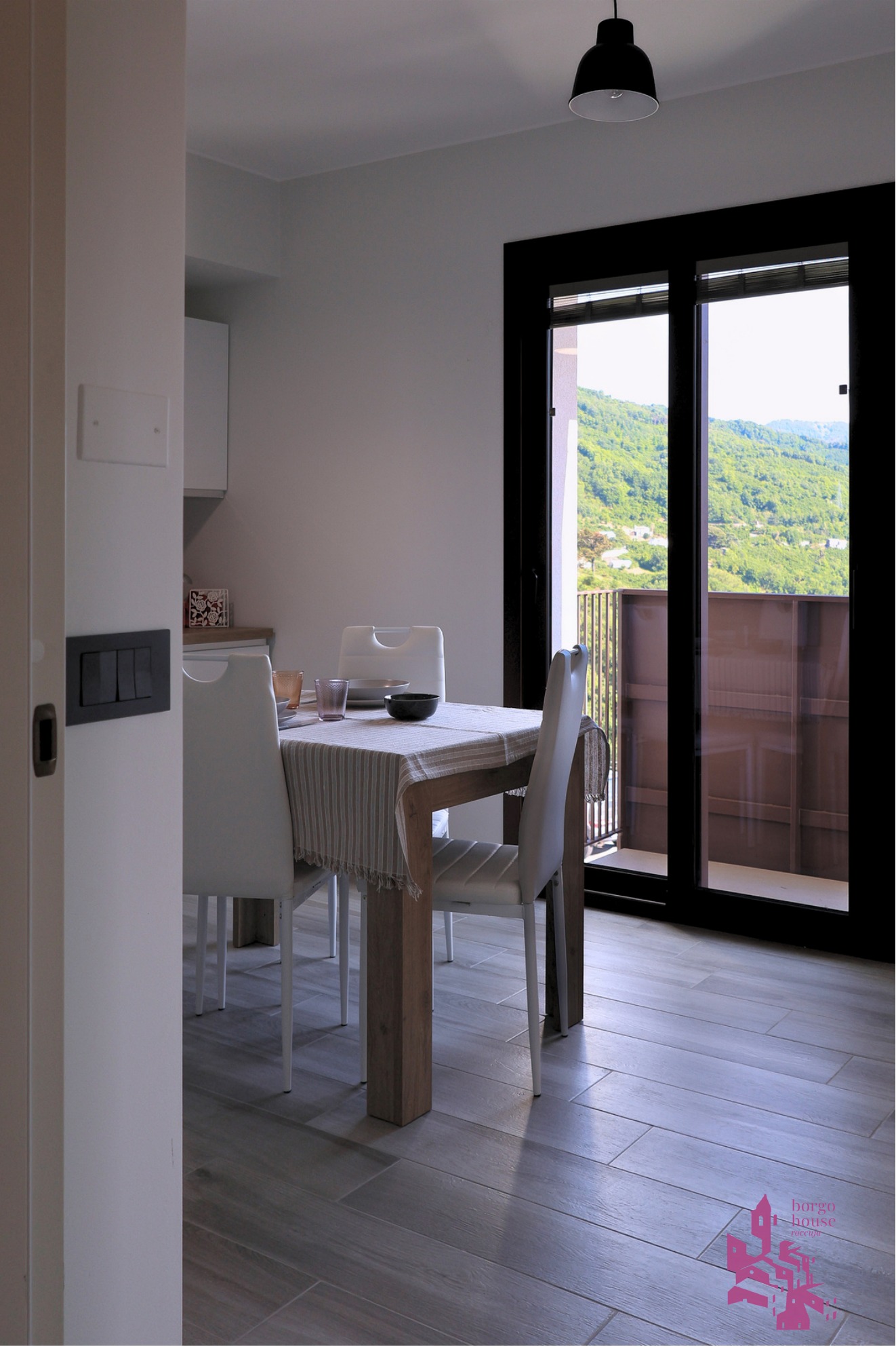 Zona pranzo accanto alla vetrata con vista sui rilievi verdi