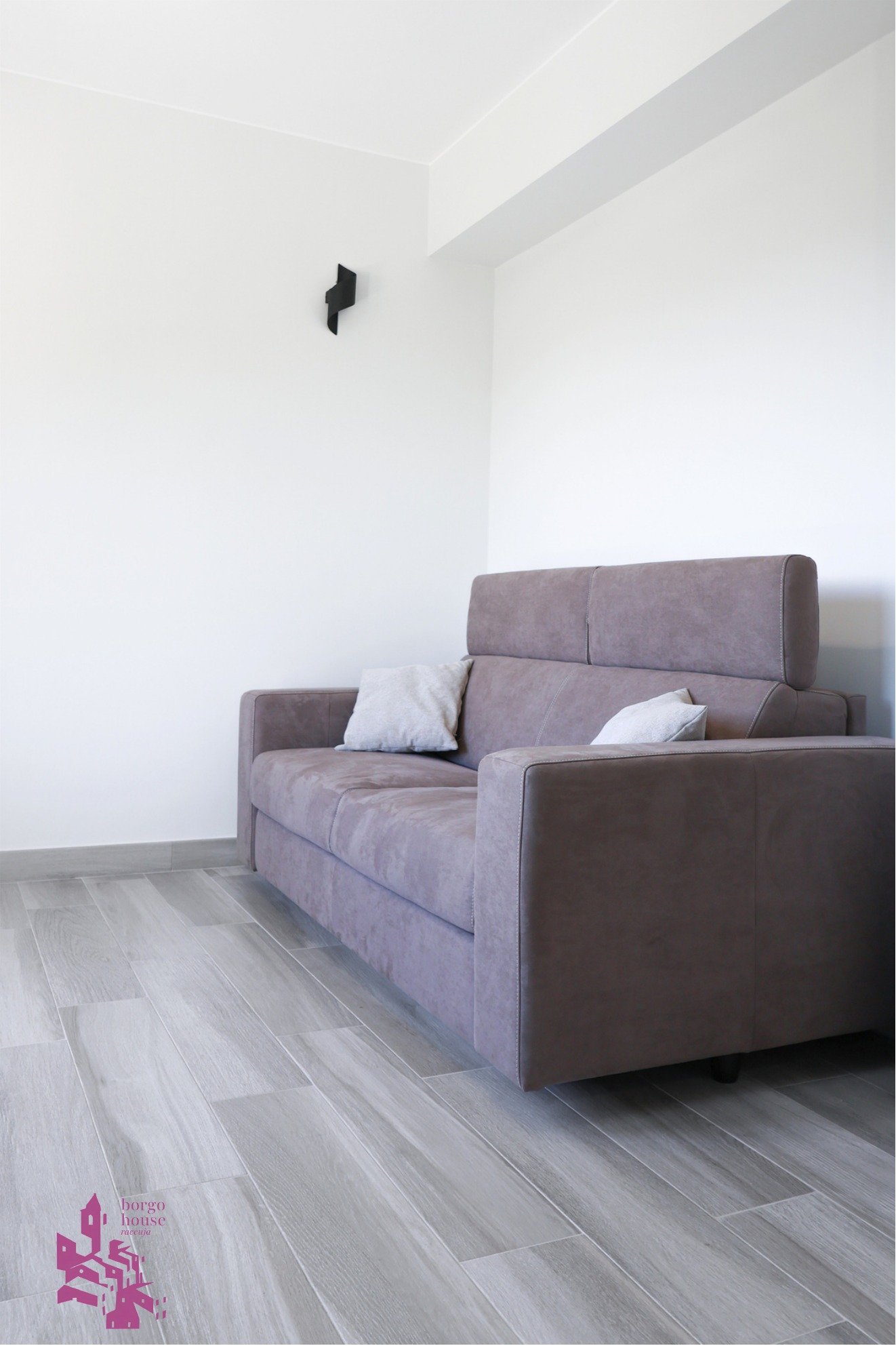 Divano letto in tessuto chiaro nel soggiorno di Borgo House